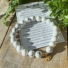 Marmorinvalkoinen rannekoru puisella alustalla